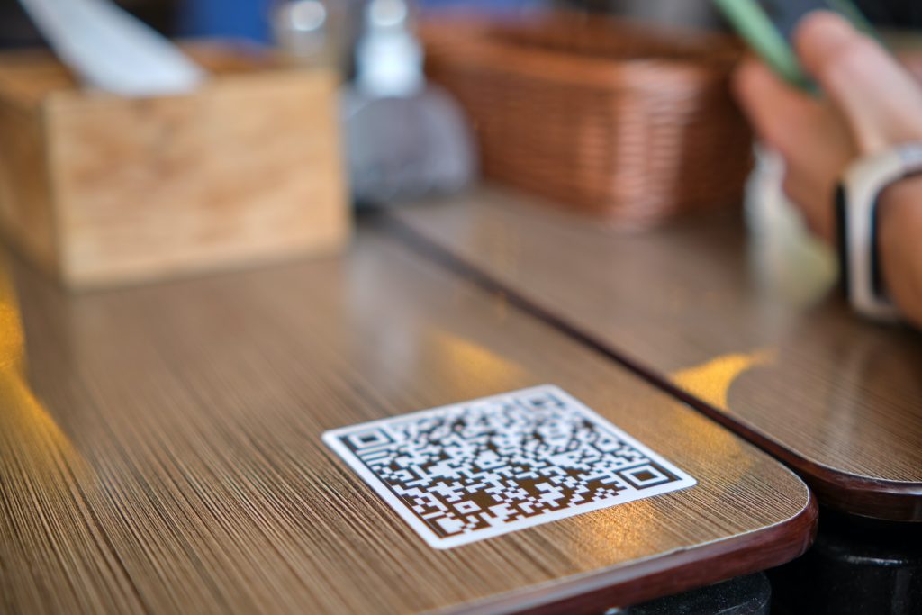 Closeup of guest hand ordering meal in restaurant while scanning qr code